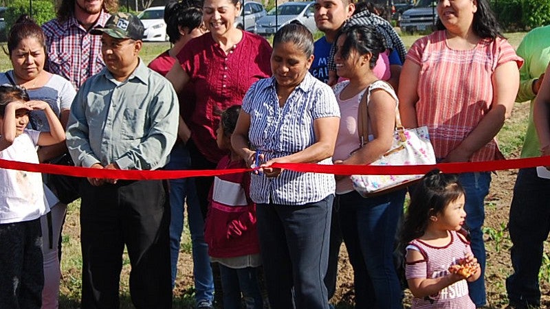 photo of people cutting ribbon on new Huerta de la Familia garden