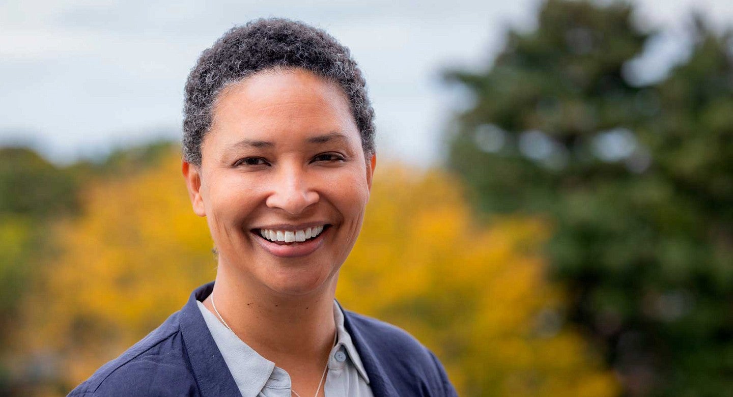 Danielle Allen smiles in front of a backdrop of trees. 